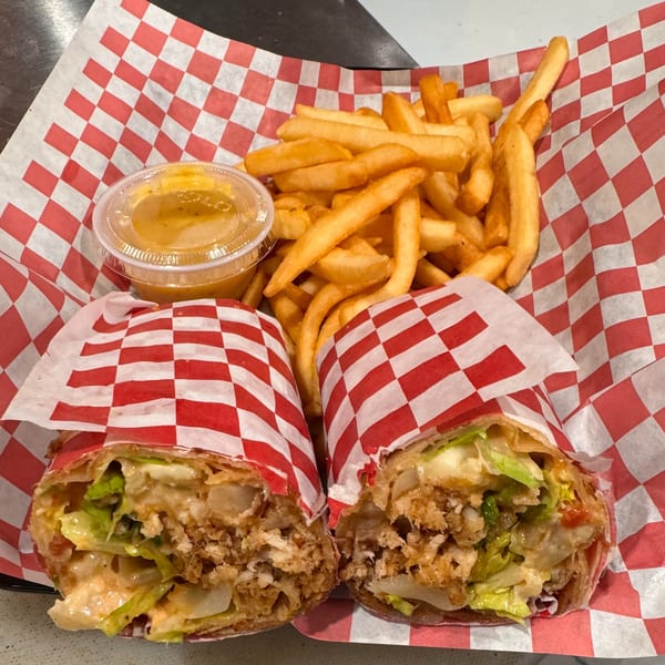Two Halwo Kismayo Grill wraps with fries and dipping sauce in a red and white checkered basket.