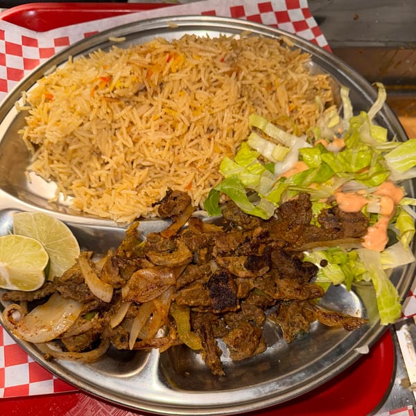 Halwo Kismayo Grill's African dish with rice, grilled meat, onions, lime, and salad.