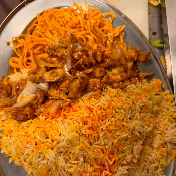 Halwo Kismayo Grill's African dish with chicken, rice, and noodles on a metal platter.